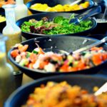 a row of woks showing prepared plant based dishes
