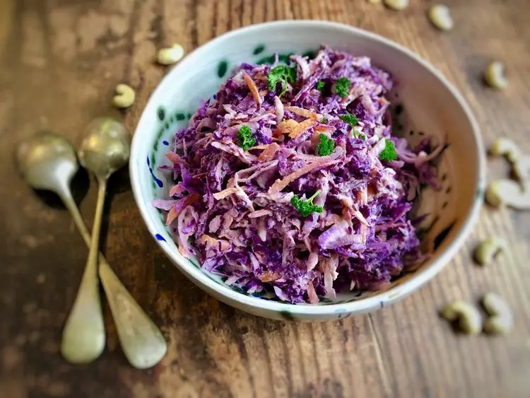 creamy vegan coleslaw served in a bowl with serving spoons