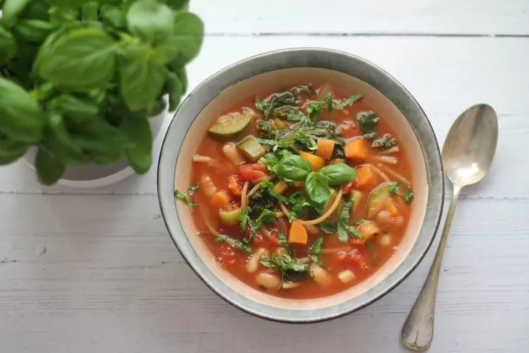 healthy minestrone soup in a bowl with plenty of basil