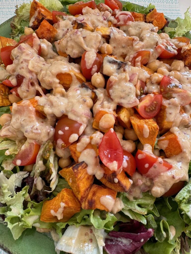 air fryer sweet potato and chickpea salad served on a large plate with dressing close up