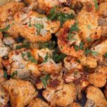 roasted cauliflower covered in spices in a bowl with lemon wedge