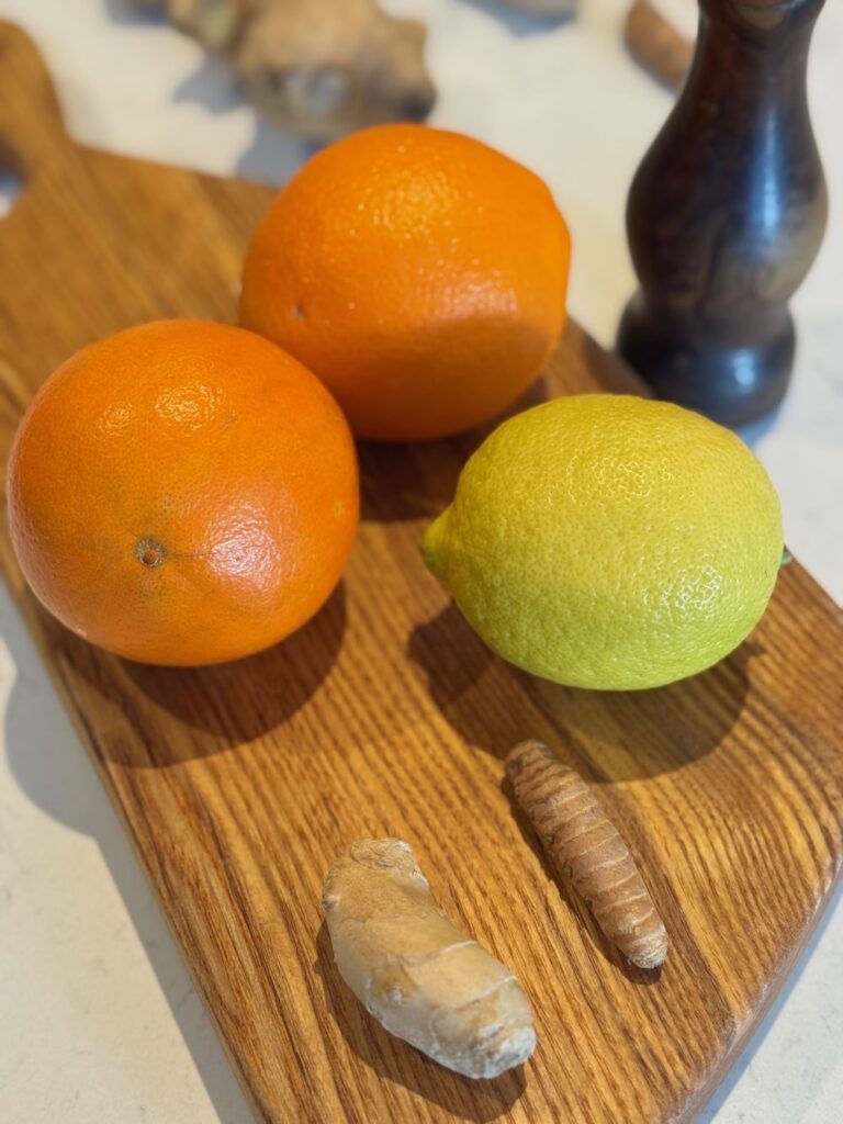 Ginger and Turmeric Citrus Shots Ingredients sitting on a chopping board