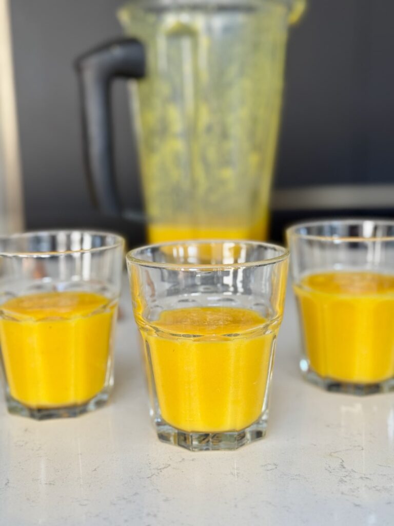 Turmeric Ginger Citrus Shots in Glasses with Blender in the background