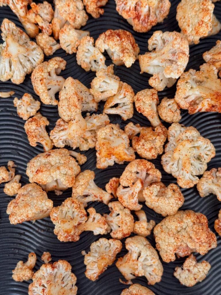 cauliflower florets with spices laid out on a roasting sheet